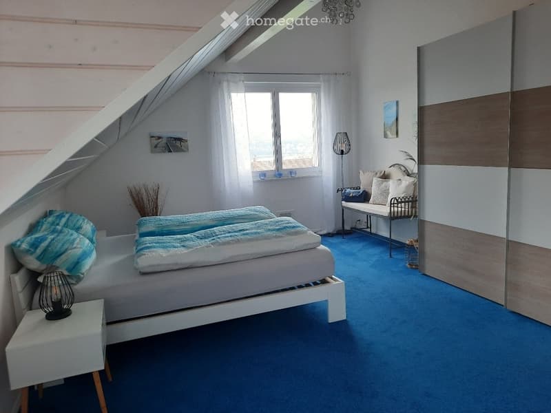 Bedroom with a bed, pillows, a nightstand, a bench, a lamp, a window, and a carpet