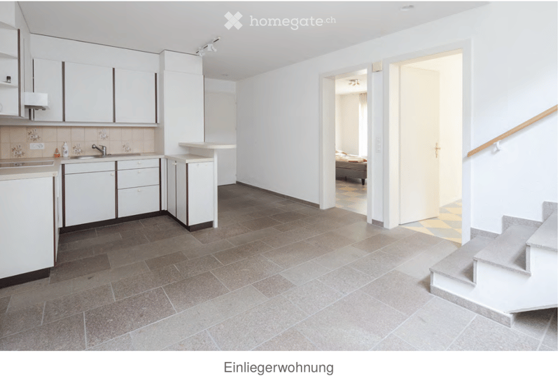 Modern kitchen with white cabinets, a sink, and a staircase leading to another room.