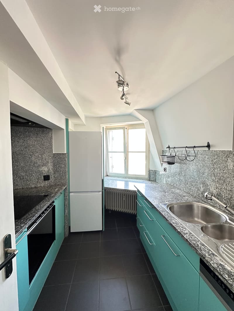 Modern kitchen with green cabinets, granite countertops, stainless steel sink, and built-in appliances.