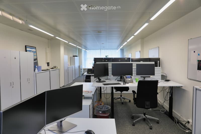 white cabinets, white desks, multiple computer monitors, chairs, trash can, whiteboards, lamps