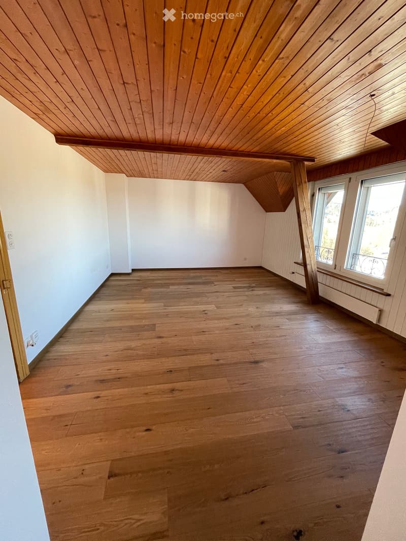 empty room with wooden floor, white walls, wooden ceiling, two windows with balcony, power outlet and switch on the wall