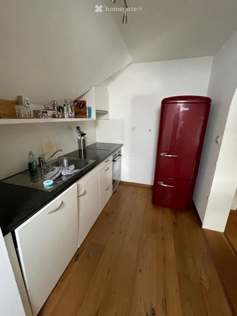 white cabinets, black countertop, stainless steel sink, silver faucet, red fridge, dishwasher, wooden floors