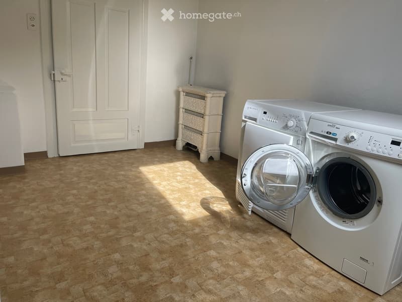 A laundry room with a white door, tile floor, and white cabinets, featuring a washer and dryer.