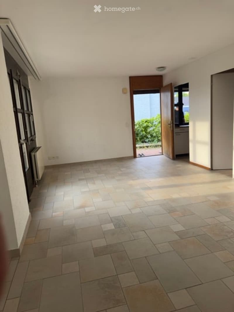 Empty room with tiled flooring, white walls, and a doorway leading to an outdoor area.
