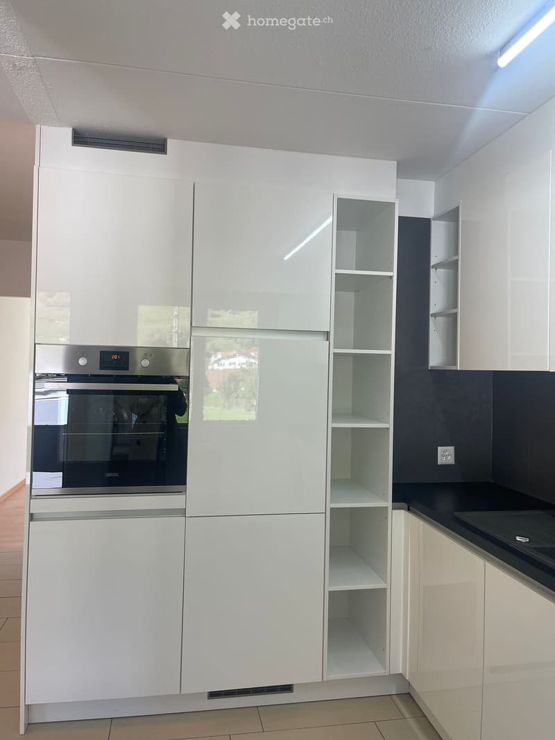 fully equipped kitchen, white cabinets, silver oven, stainless steel fridge, black countertops