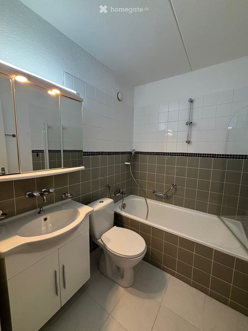 Bathroom with bathtub, toilet, sink, mirror, and shower handle.