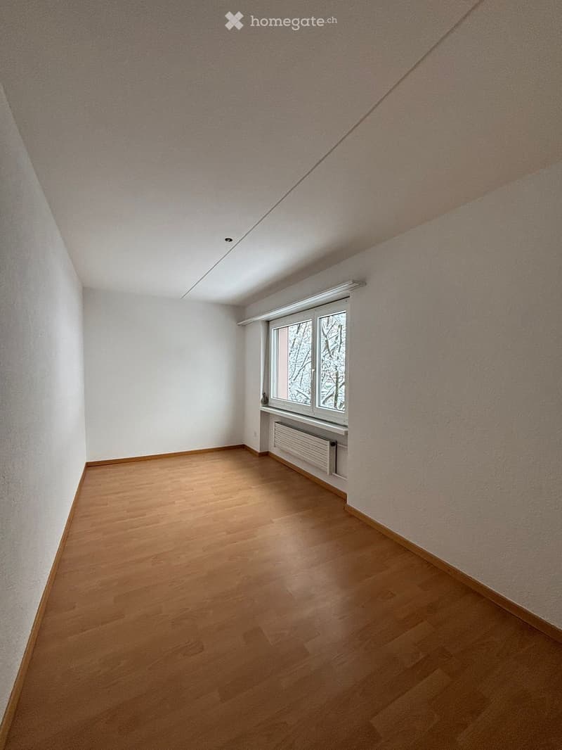 empty room, white walls, wooden floor, window with radiator below