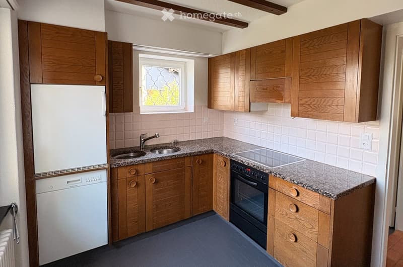 Compact kitchen with wooden cabinets, granite countertop, stainless steel sink, and built-in appliances including a refrigerator, dishwasher, and oven.