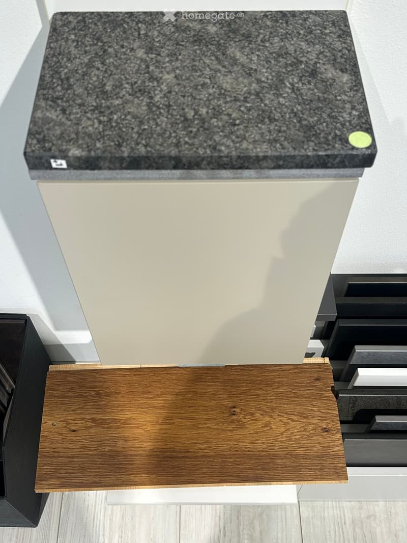 Close-up view of a kitchen countertop with a granite top and light-colored cabinets.