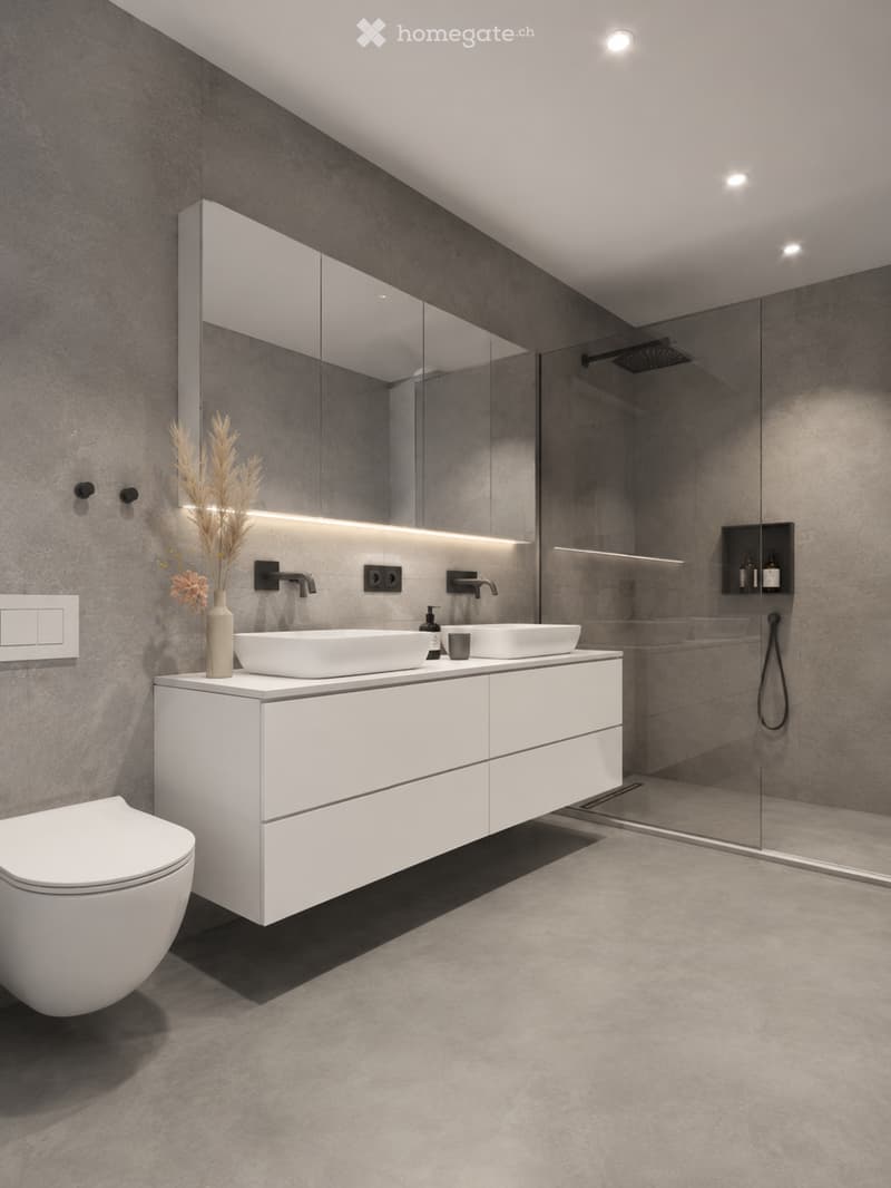 Modern bathroom with white sink, toilet, large mirror, and glass shower enclosure. Features grey walls and floor, sleek fixtures, and decorative vase with dried plants.