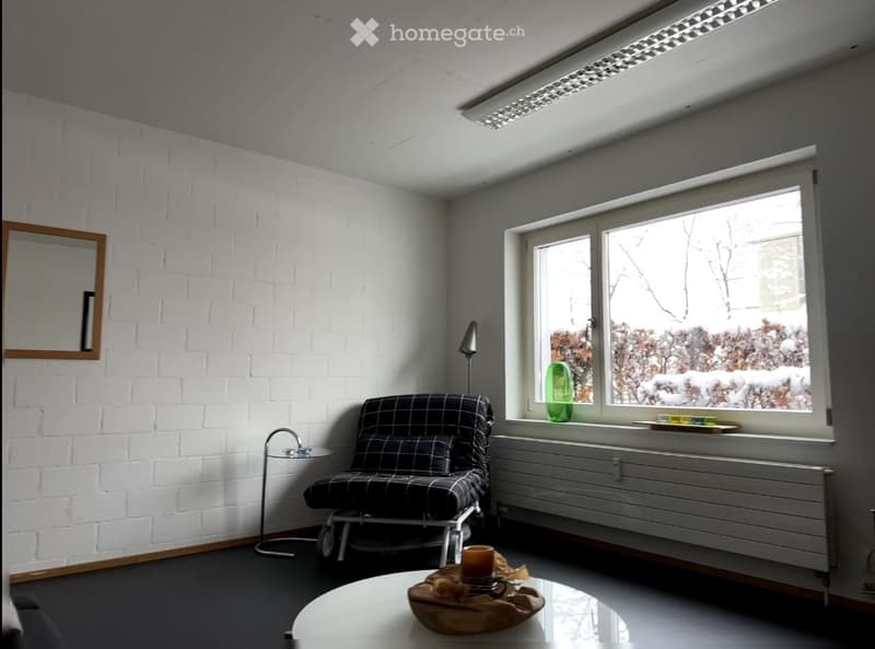 Modern living room with white brick walls, large window, sofa, coffee table, table lamp, and decorative items.
