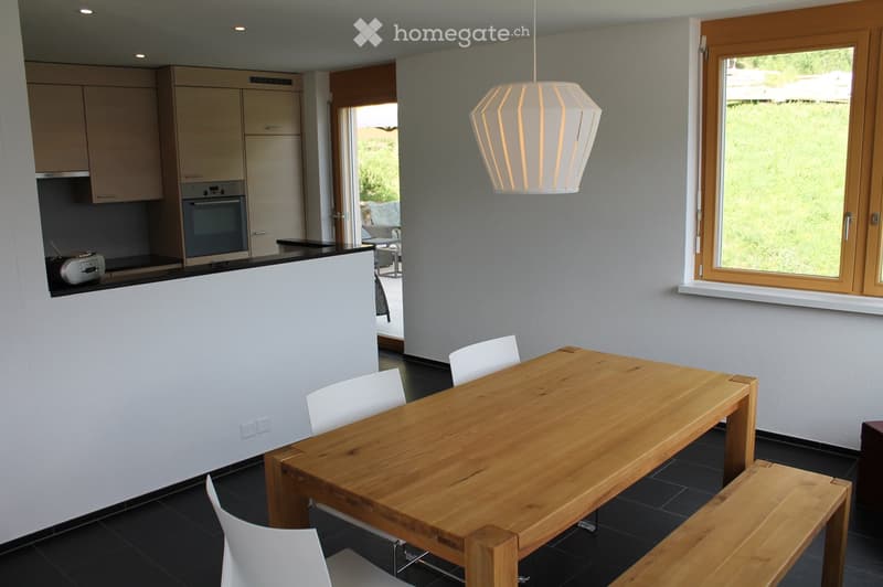 Modern kitchen and dining area with a wooden dining table, white chairs, a bench, and built-in cabinets. An oven and microwave are visible in the kitchen area.