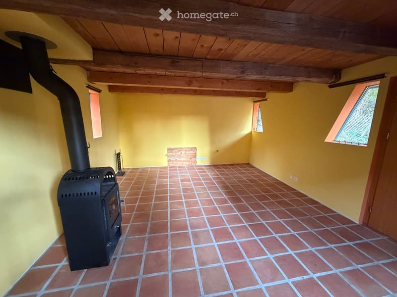 Empty room with yellow walls, red floor tiles, a fireplace, a wooden ceiling, and two small windows