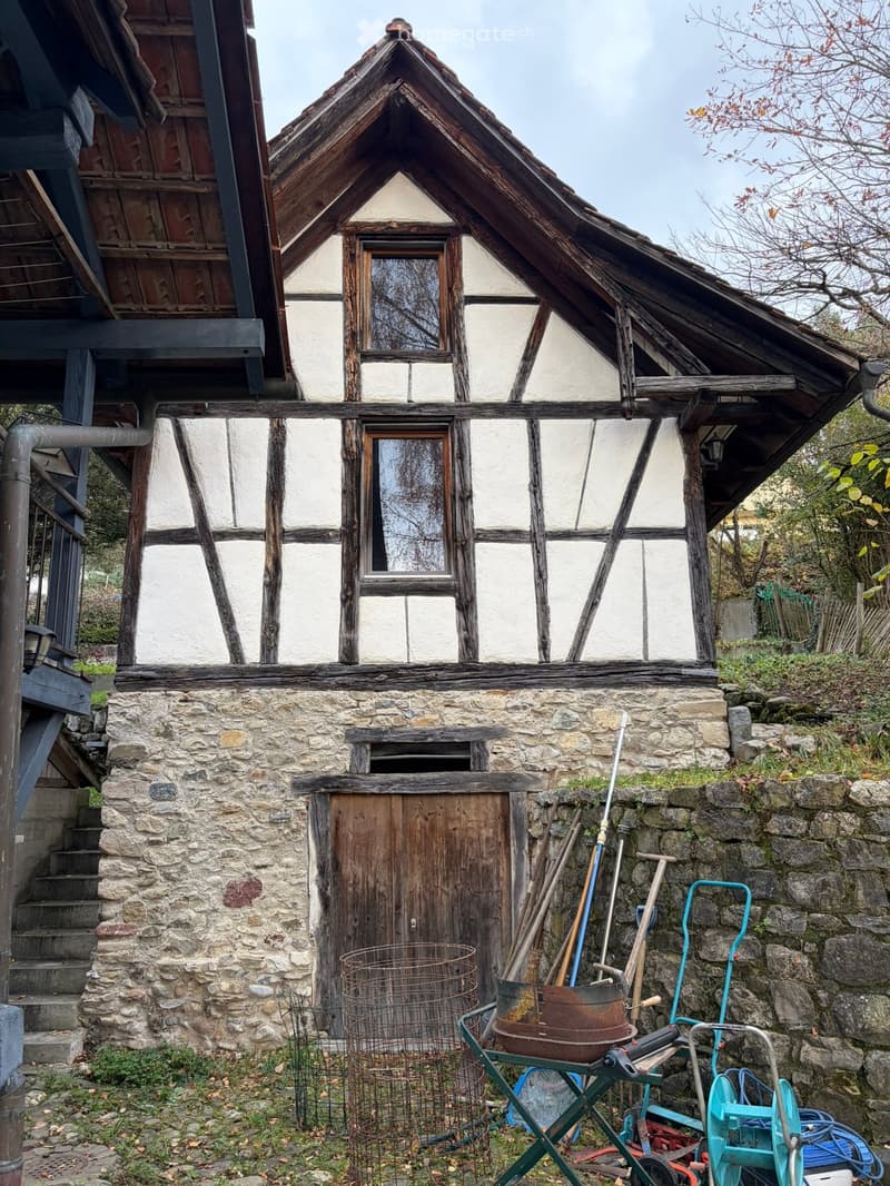 2 story stone house, brown wooden beams, white paint, wooden door, stone stairs