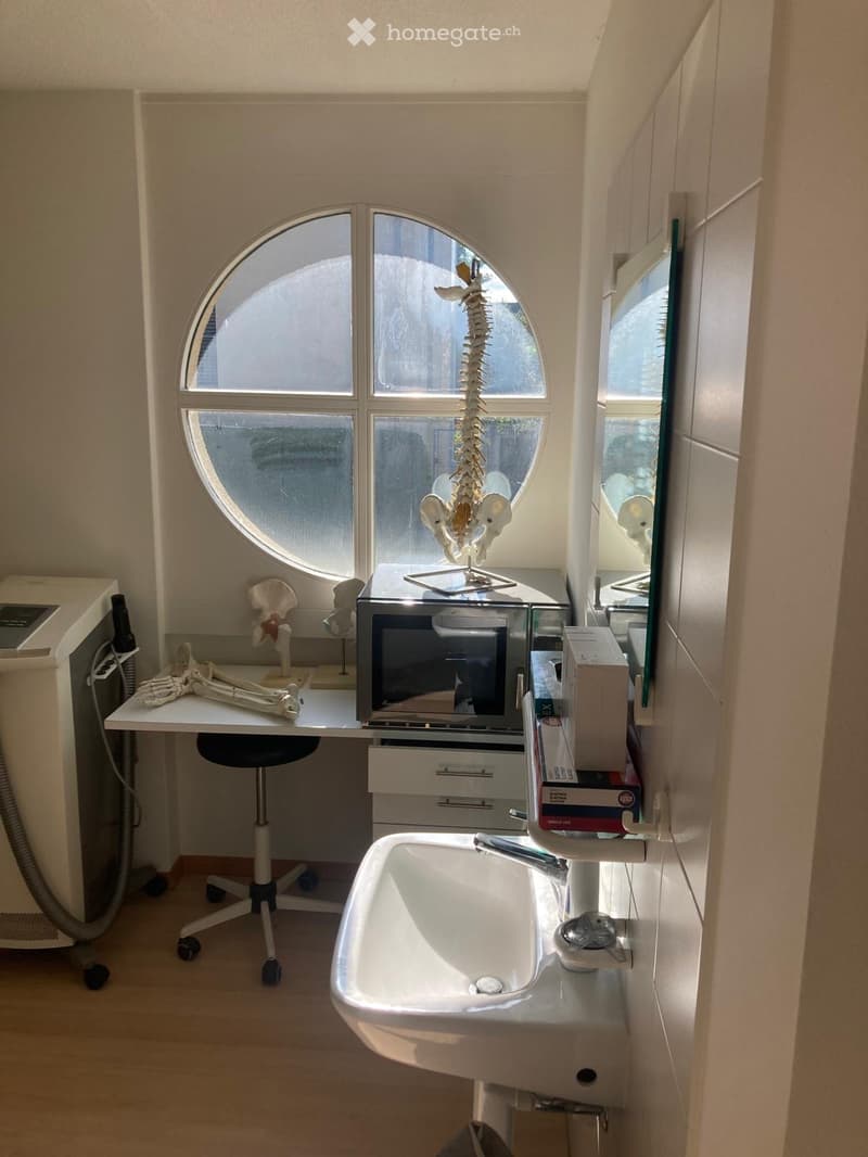 small room with desk, chair, microwave, skeleton model, sink, mirror