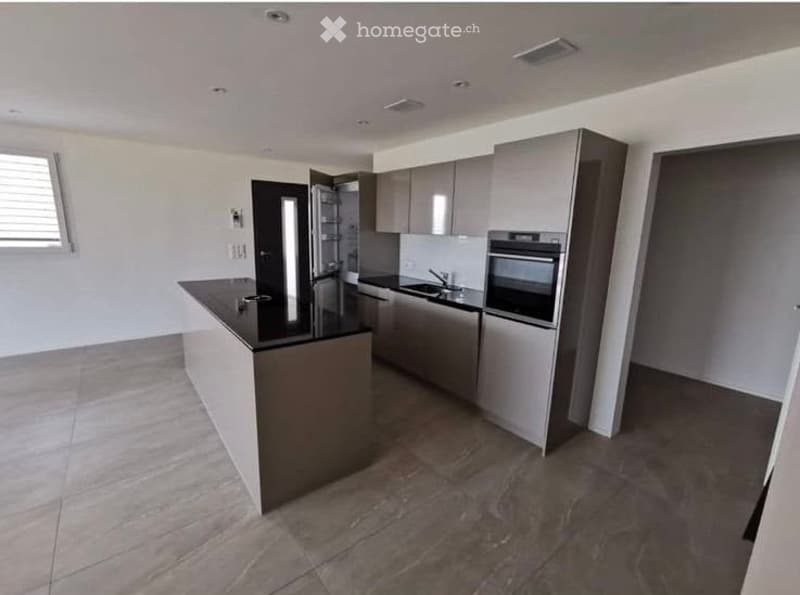 Modern kitchen with a central island, stainless steel appliances, and grey cabinets.