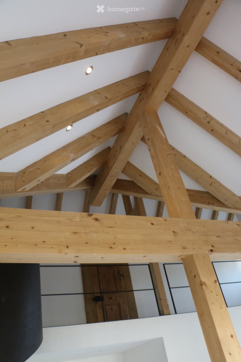 Exposed wooden beams and ceiling lights in a modern interior space.