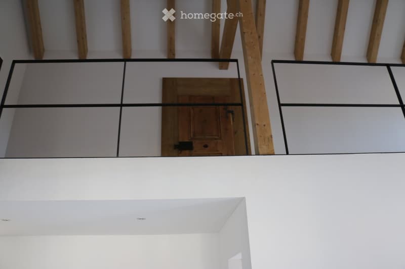 A modern floor plan with a raised ground floor, featuring a wooden door and glass panels, with exposed wooden beams on the ceiling.