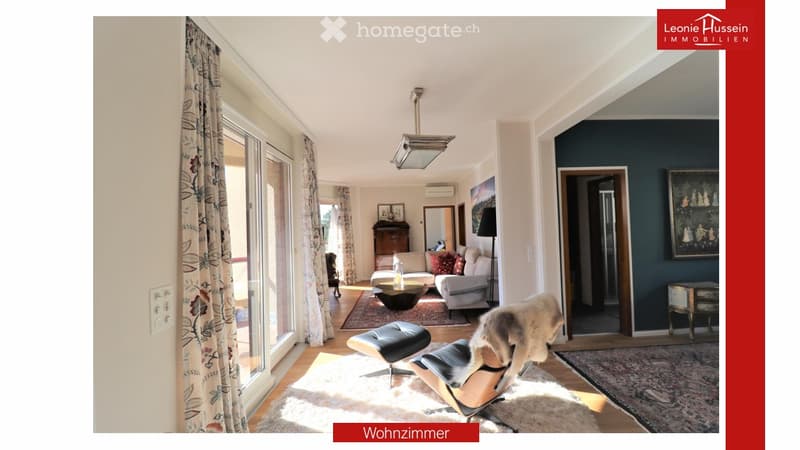 Bright living room with large windows, a sofa, coffee table, ottoman, chair, mirror, and picture frame.
