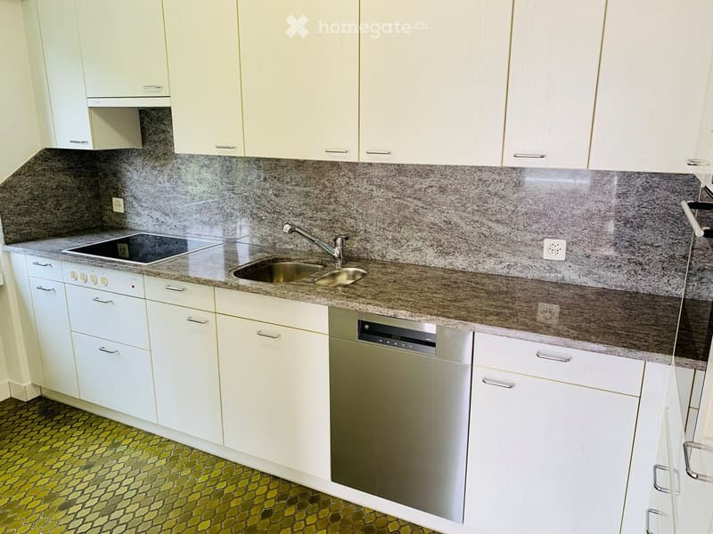 Kitchen. Modern kitchen with white cabinets, granite countertop, stainless steel sink and dishwasher, electric stove, and a green tiled floor.