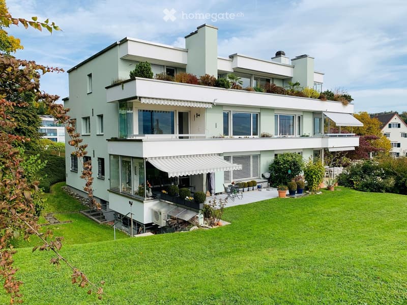 House. Modern two-story house with white exterior, large windows, and a well-maintained garden with lawn, potted plants, and outdoor seating.