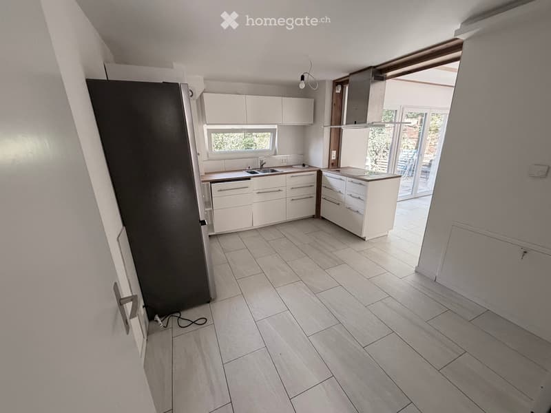 Modern kitchen with white cabinets, a stainless steel refrigerator, a sink, and a window overlooking the outdoor area.