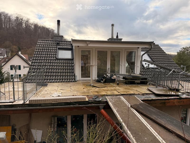 Roof terrace of a modern house with glass doors, metal railings, and scattered construction materials.