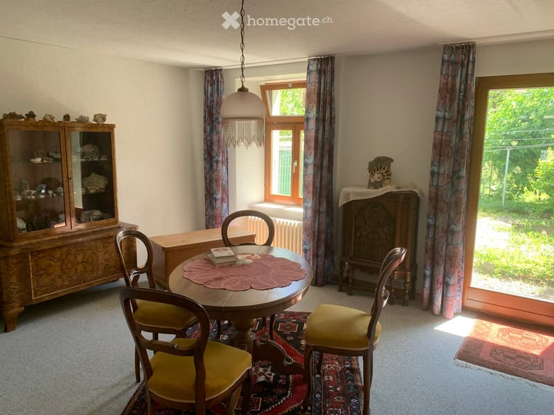 Dining room with a round wooden table, four chairs, a wooden cabinet, and a hanging lamp.