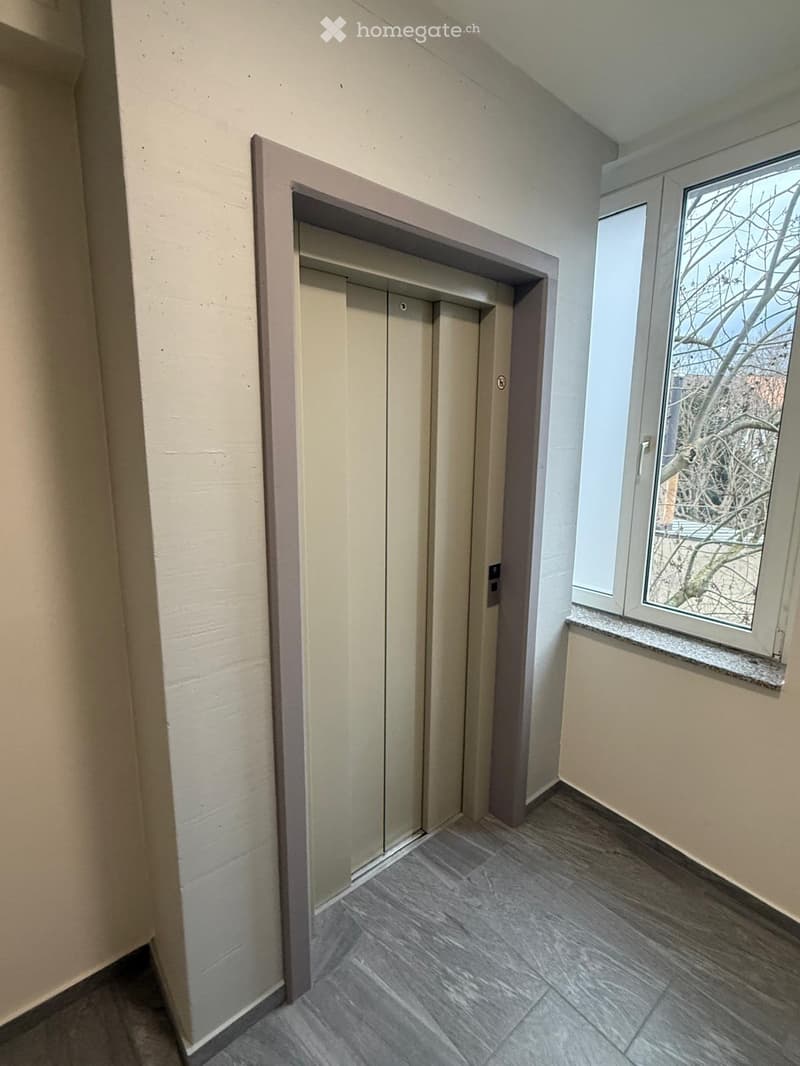 elevator shaft, light gray tile flooring, white walls, window