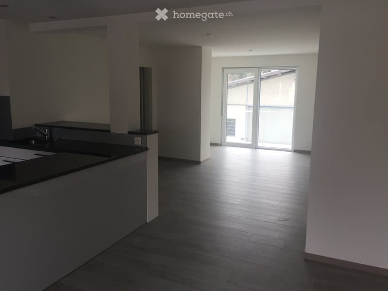 Empty room with wooden flooring, white walls, and a sliding glass door leading to a balcony.
