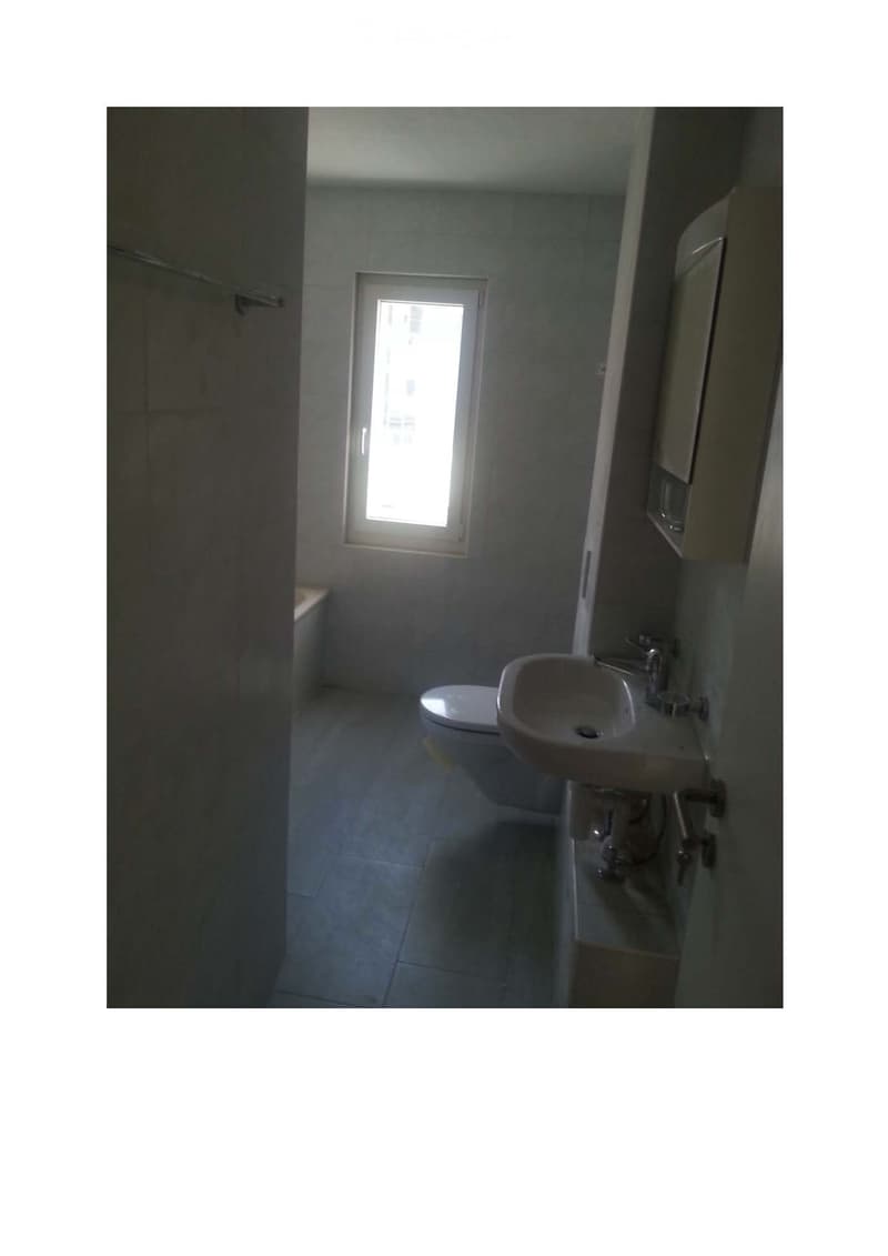 Bathroom with a sink, faucet, toilet, and bathtub, featuring tiled walls and a window providing natural light.