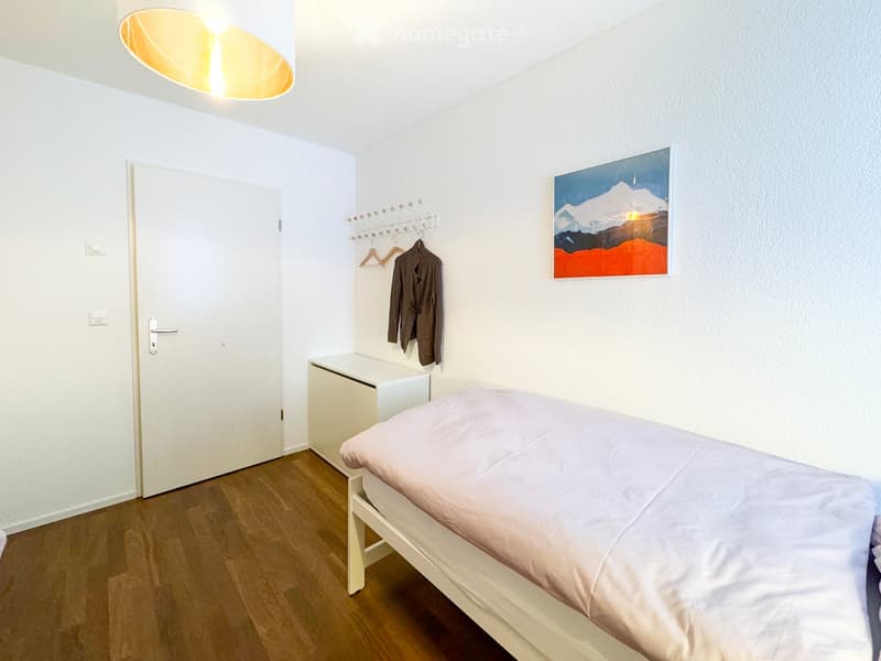 Minimalist bedroom with a single bed, nightstand, coat rack, and a painting on the wall.
