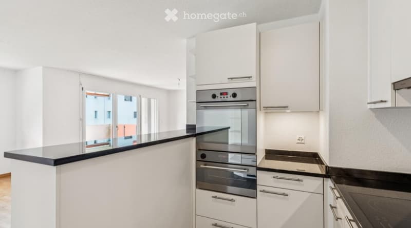 Modern kitchen with white cabinets, stainless steel oven, and black countertop.
