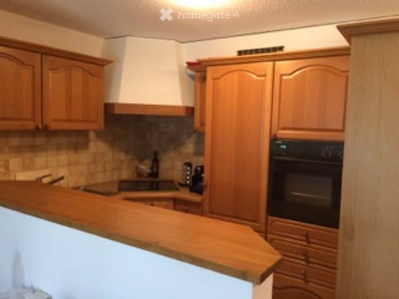 Wooden kitchen with light-colored cabinets, a built-in oven, and a countertop. The stove is centrally located, and the space is well-lit with natural light.