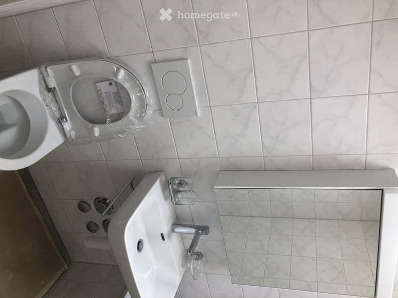 small bathroom with white tiles, toilet, sink, and mirror