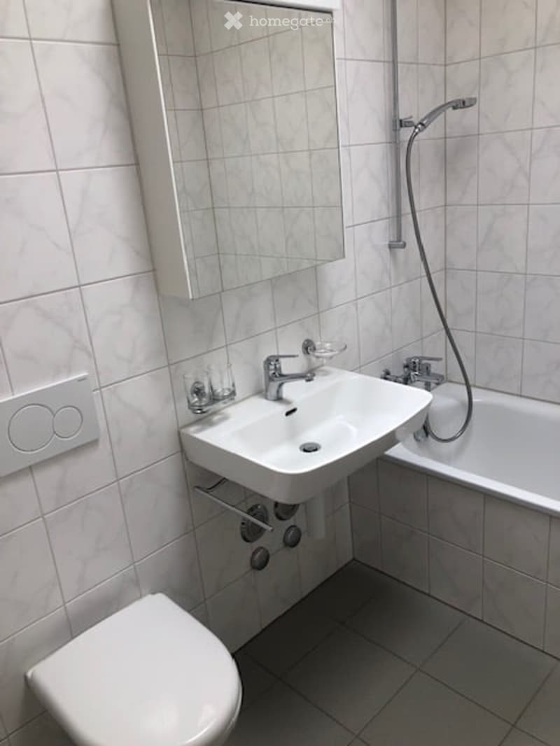 white tile floor, white tile wall, sink, mirror, bathtub, toilet, shower head