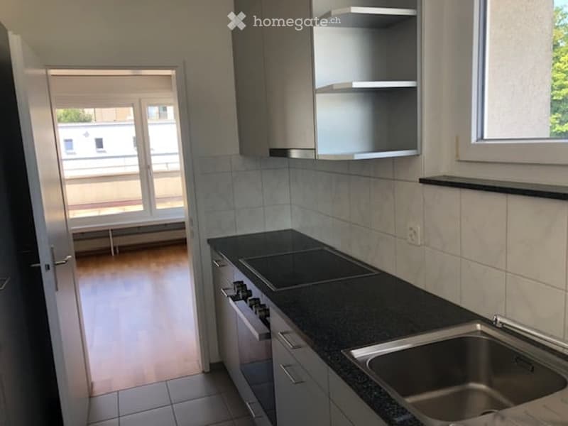 Stainless steel sink, black countertop, tile flooring, stainless steel appliances