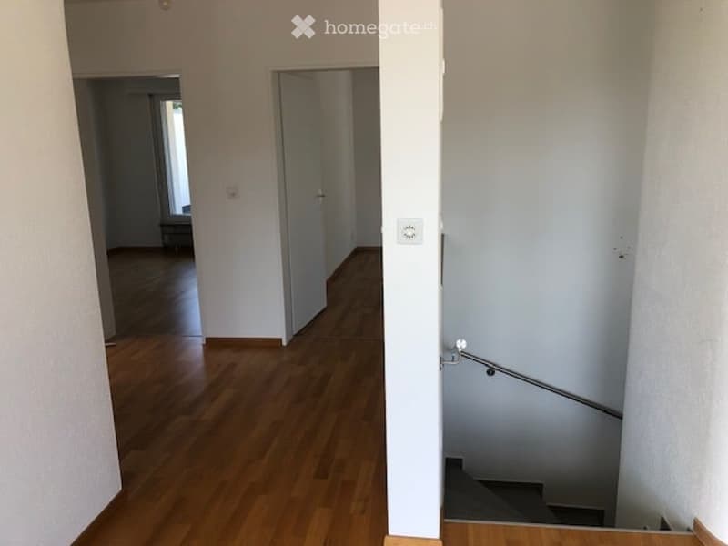 wooden floor, white walls, white doors, no furniture, stairs to another floor