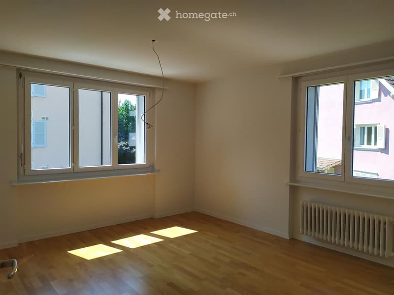 empty room, wooden floor, white walls, two large windows, white radiator