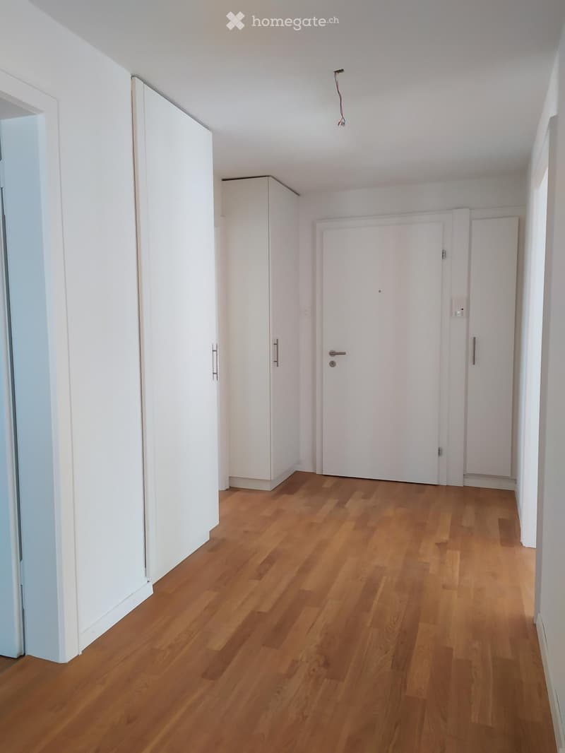 Empty room with wooden floor, white walls, and white doors.