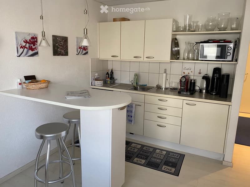 kitchen area with central island, countertop, cabinets, sink, appliances, baskets, rugs, wall art, lamps
