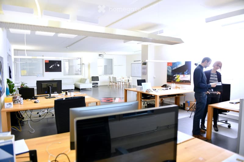 modern, minimalist office space with multiple desks, chairs, computers, whiteboards, and a couch