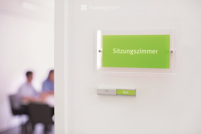 Room door with sign, 'Sitzungszimmer', blurry background of people sitting at table