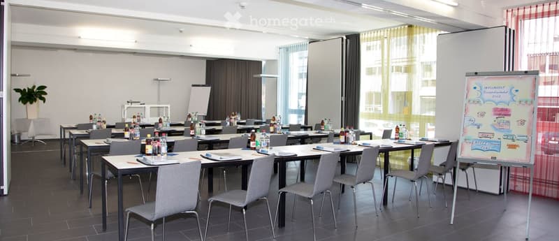 large room, tables and chairs, whiteboards, whiteboards on the wall, plants, ceiling lamps, windows with curtains