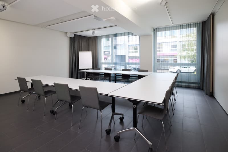 Meeting room, long table, chairs, whiteboard, two windows, no people