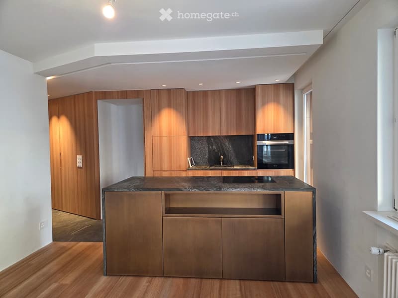 Modern kitchen with wooden cabinets, granite countertop, and built-in oven. Features recessed lighting and a sleek design.