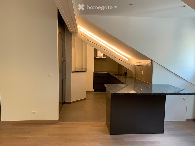 Modern kitchen with dark countertops, white cabinets, and a sleek design, featuring a sink and faucet.