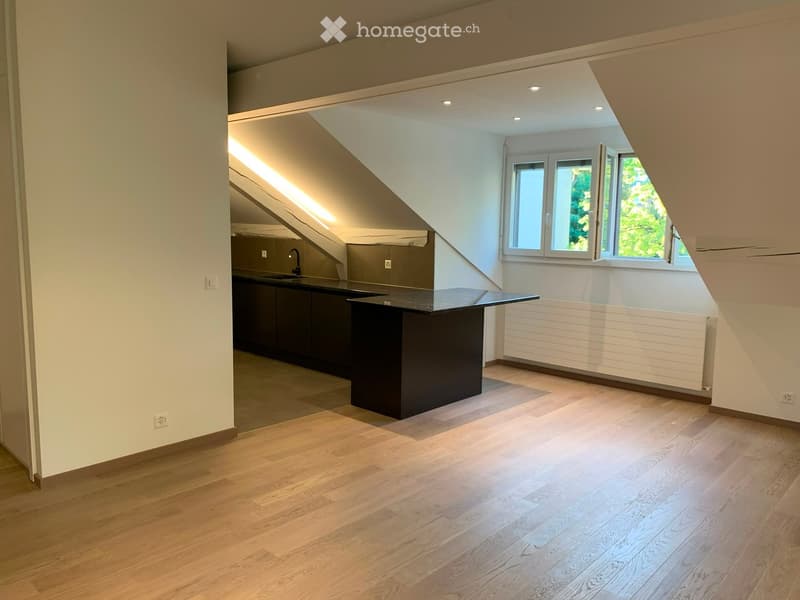 Modern kitchen with wooden flooring, black kitchen island, sink, and ample natural light from large windows.