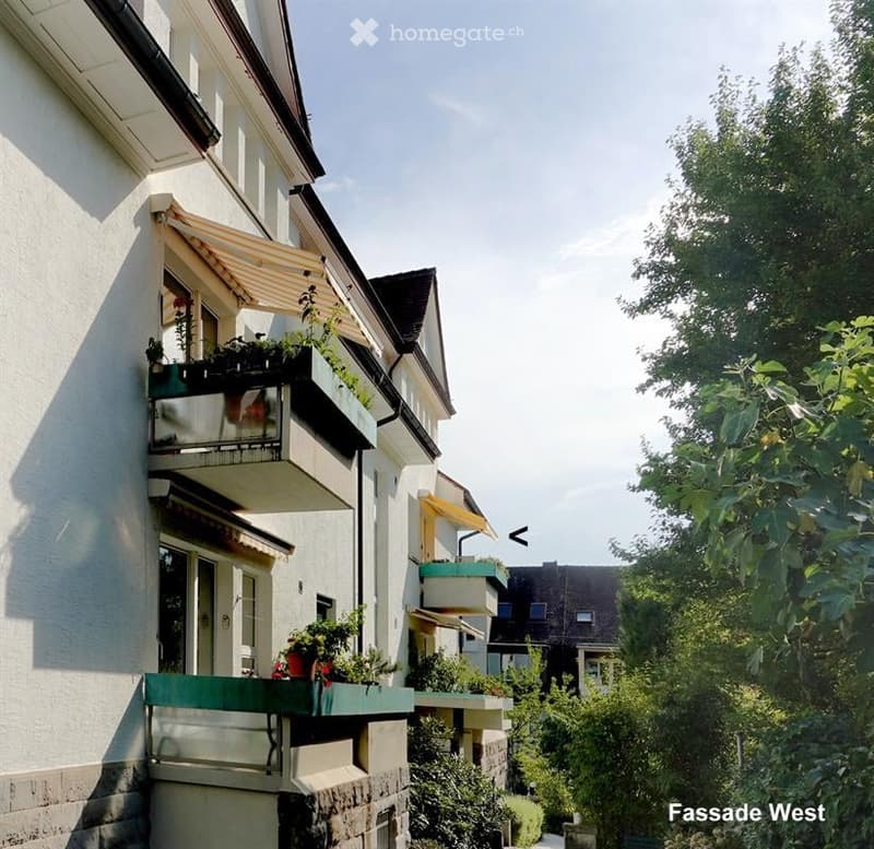 Multi-story residential building with balconies, awnings, and potted plants.