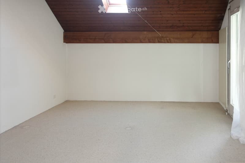 Empty room with white walls, wooden ceiling, and concrete floor. No furniture or equipment visible.